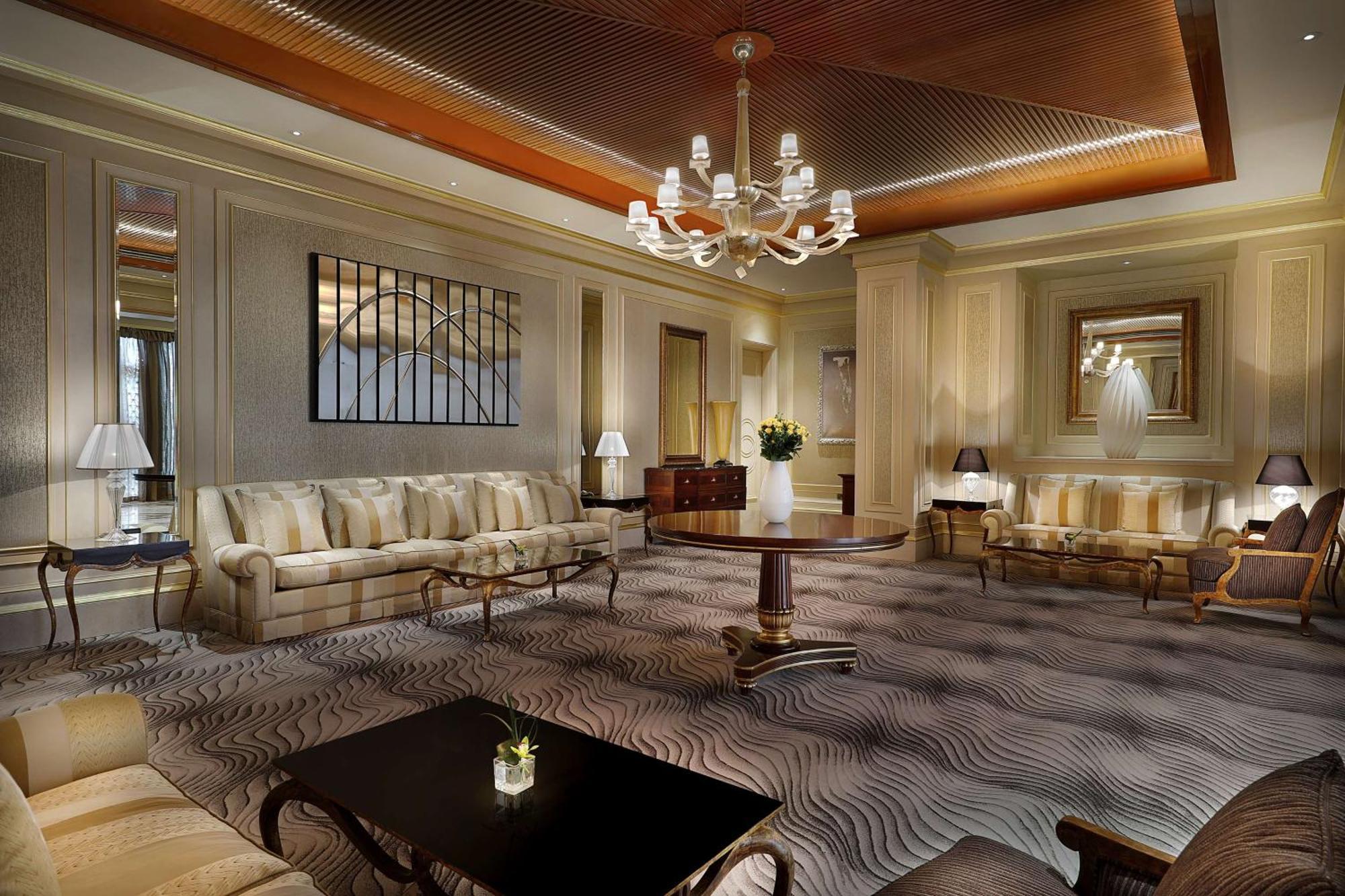 Hilton Riyadh Hotel & Residences Εξωτερικό φωτογραφία The photo depicts an elegant and well-appointed living room or lounge area. It features a soft color palette with beige and cream tones throughout. 

1. **Furniture**: There are two plush sofas, a round wooden coffee table in the center, and a couple