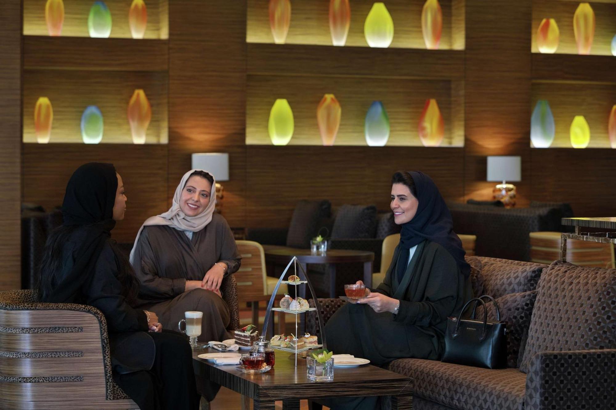 Hilton Riyadh Hotel & Residences Εξωτερικό φωτογραφία The photo shows three women sitting together in a cozy, well-decorated lounge. They appear to be enjoying each other's company, engaged in conversation and possibly sharing tea or refreshments. The setting features soft, modern lighting with decorati