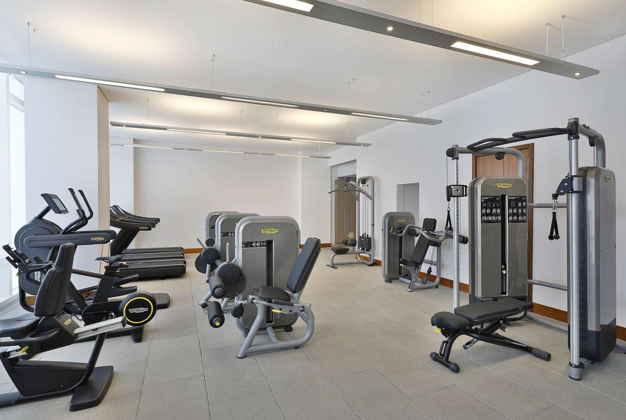 Hilton Riyadh Hotel & Residences Εξωτερικό φωτογραφία The photo shows a modern gym or fitness center with various exercise equipment. On the left, there are several treadmills, while the center features a range of weight machines. There is a multi-station gym equipment, and a bench press is also visible